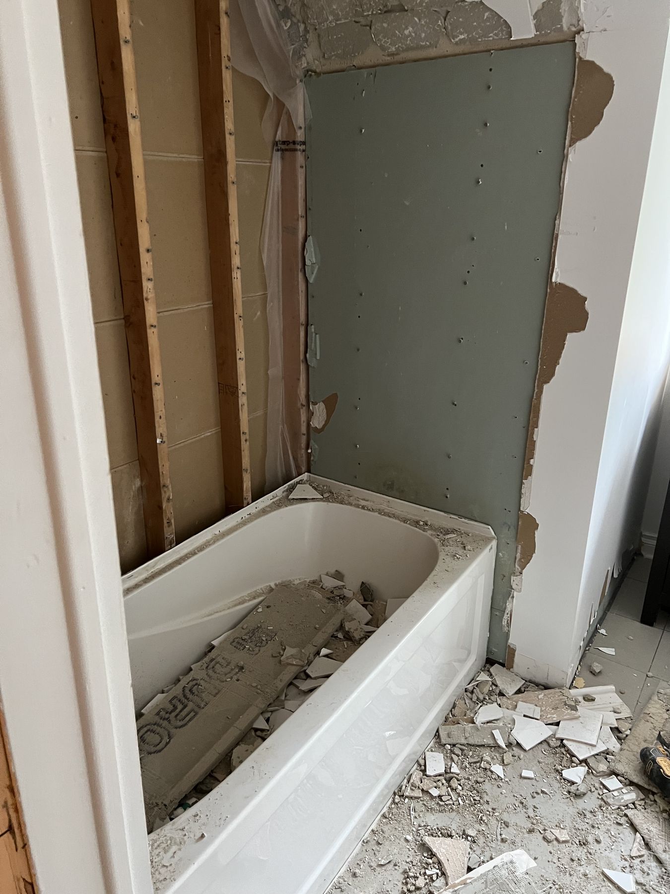 Old bathroom during demolition, with the original tub and wall tile being removed