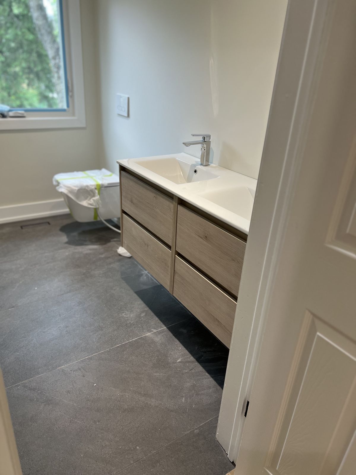 Compact new bathroom with a floating vanity and slate-grey floor tile