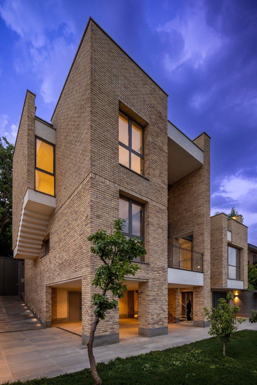 Completed three-storey brick house at dusk with its windows lit