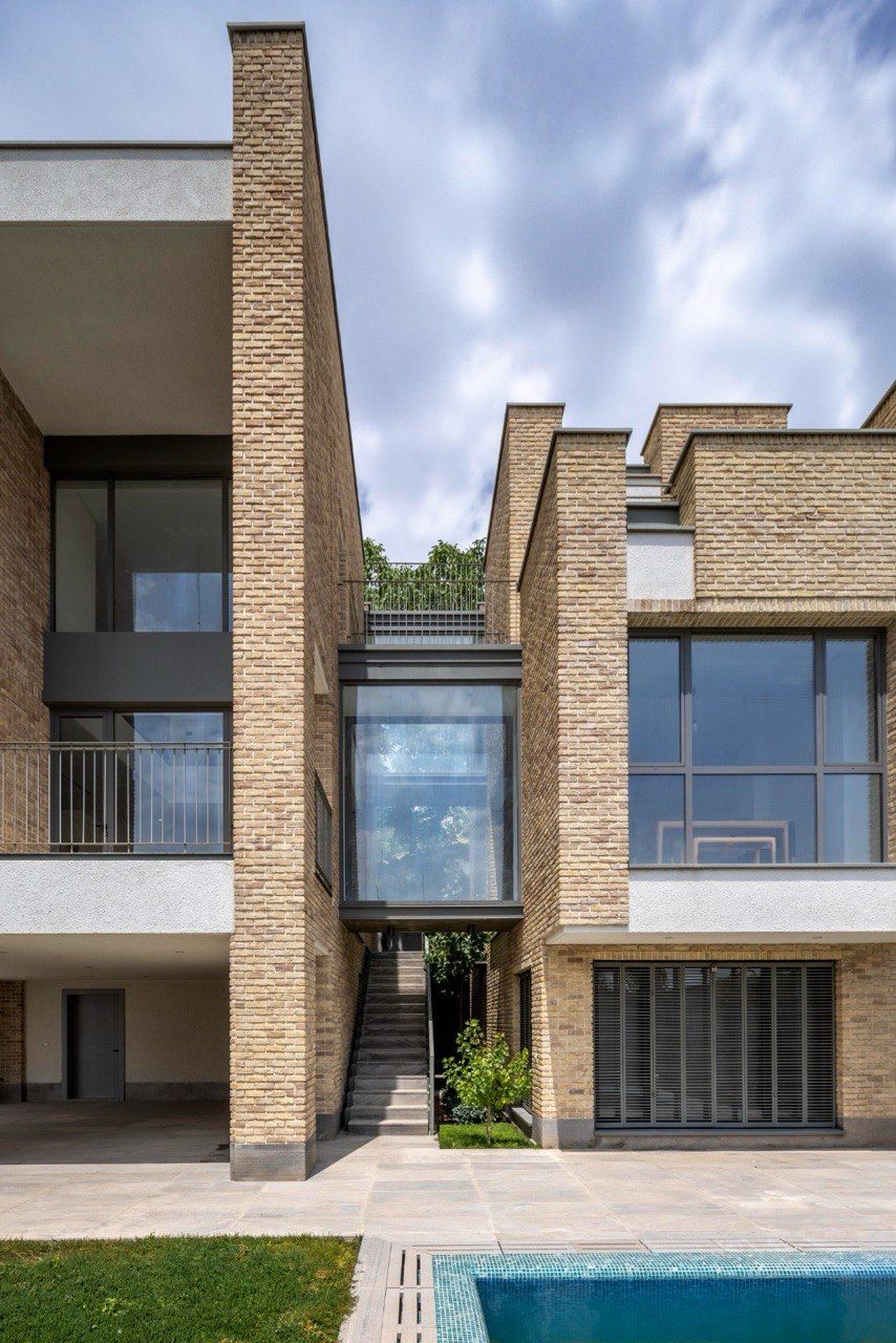 Rear view of a modern brick house with large windows facing a garden